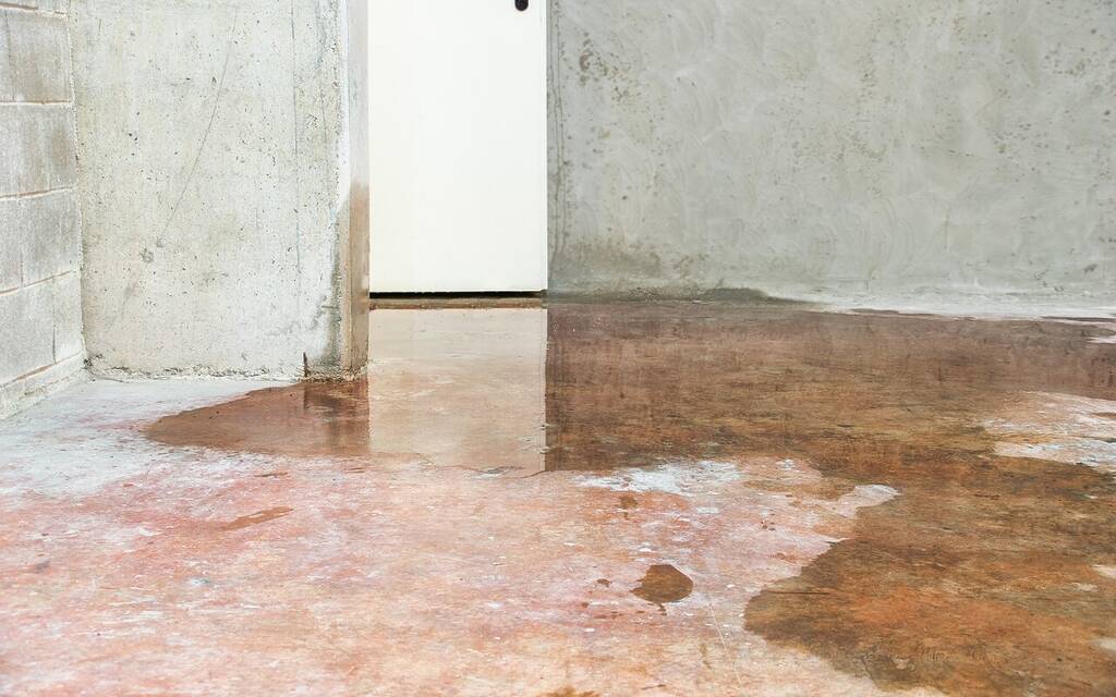 A flooded residential basement floor with standing water on the concrete surface.
