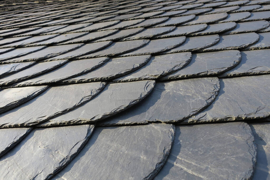A close up of slate shingles overlapping one another on a residential roof